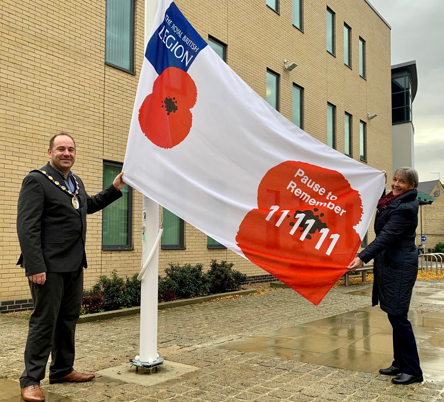 Picture of Chair, Cllr Michael Burke, holding RBL flag with Judith Armstrong, Secretary of The Royal British Legion Huntingdon & District Branch.